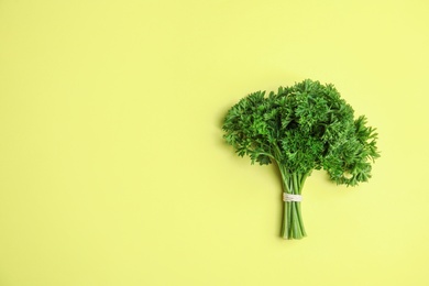 Photo of Bunch of fresh green parsley on yellow background, top view. Space for text