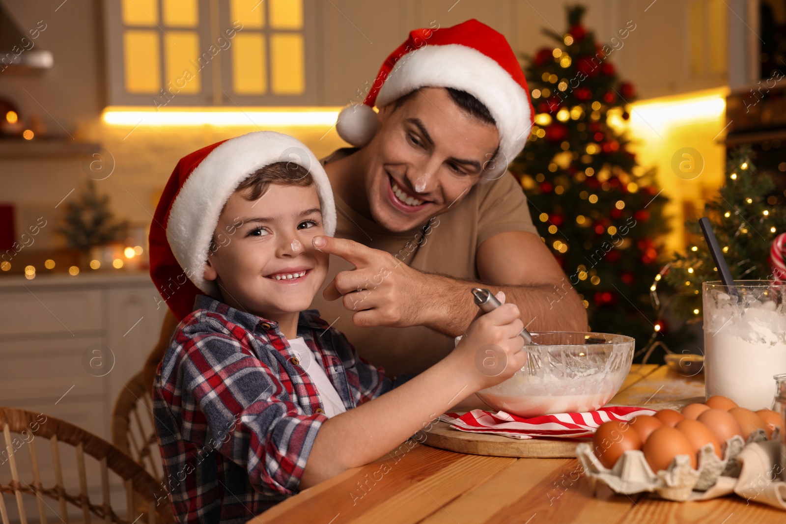 Photo of Happy father and his son making dough for Christmas cookies at home
