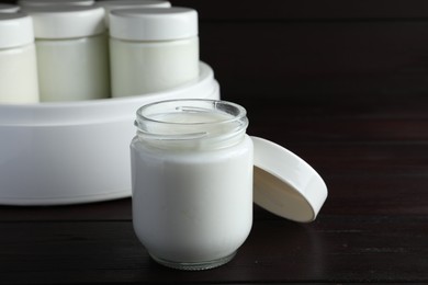 Glass jar with tasty yogurt on wooden table