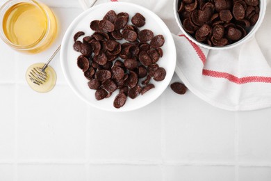 Photo of Breakfast cereal. Chocolate corn flakes and milk in bowl on white tiled table, flat lay. Space for text