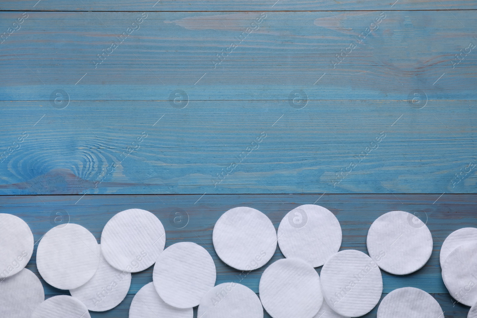 Photo of Many clean cotton pads on light blue wooden table, flat lay. Space for text