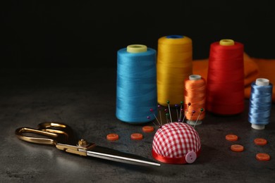 Composition with different sewing items and fabric on grey stone table