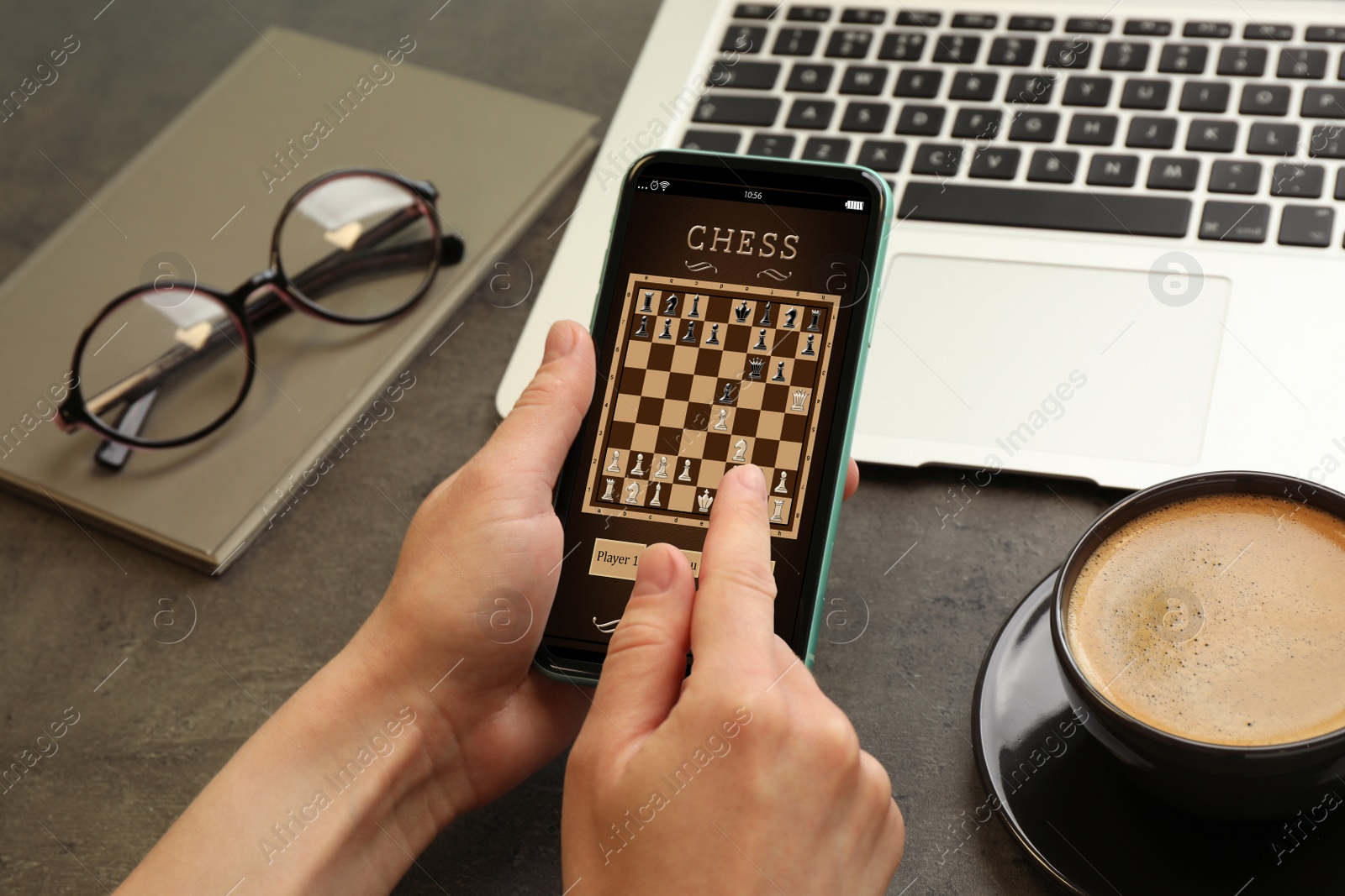 Image of Woman playing online chess on smartphone at table, closeup