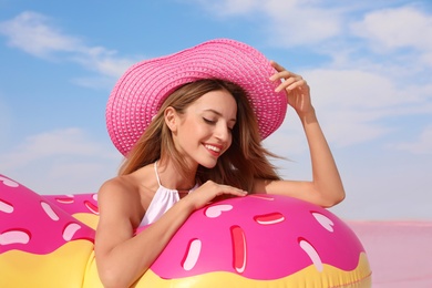 Photo of Beautiful woman with inflatable ring near pink lake