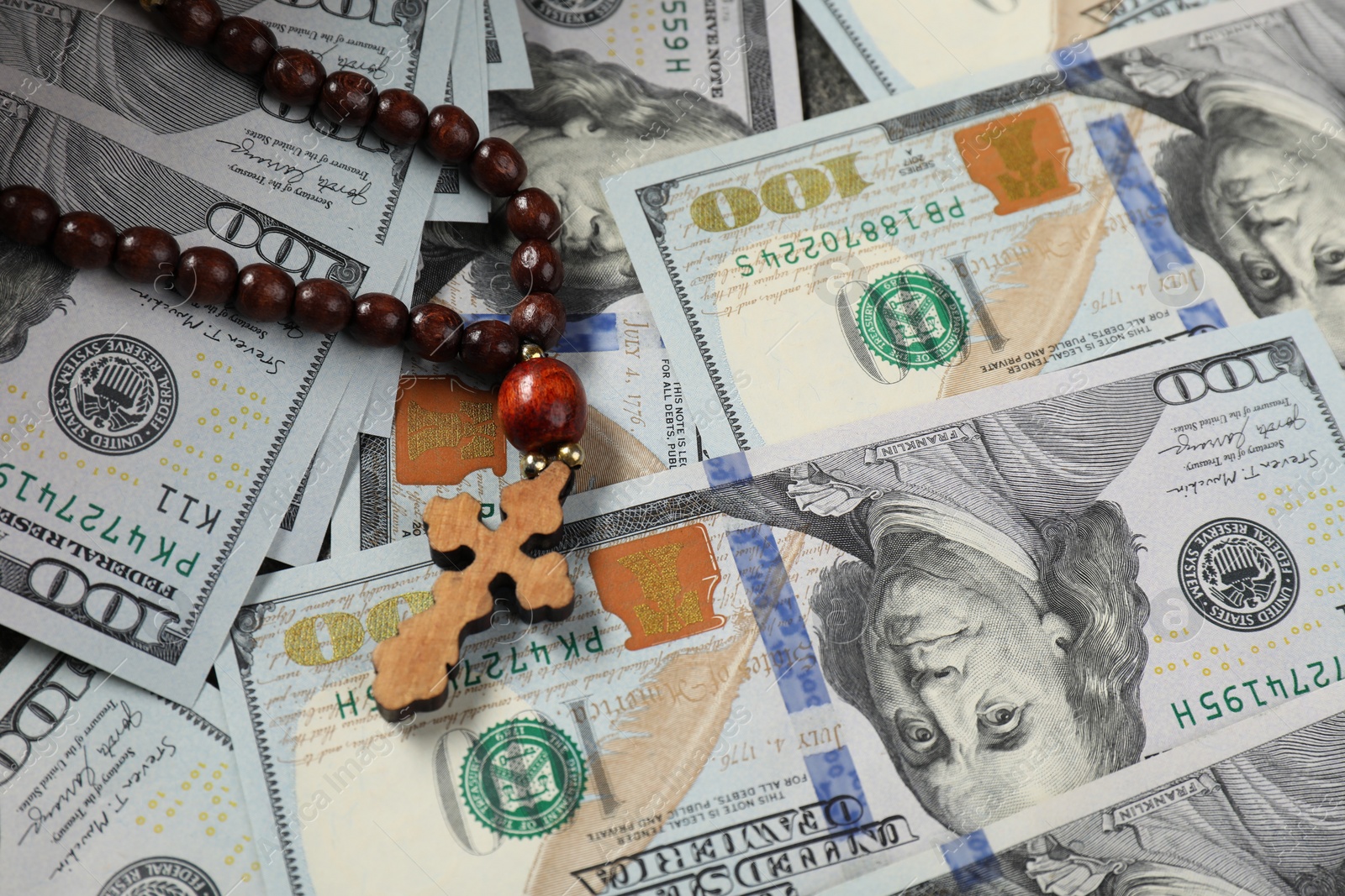 Photo of Wooden cross on dollar banknotes, closeup view