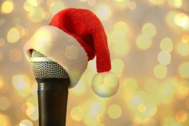 Image of Christmas music. Microphone with Santa hat on blurred background, bokeh effect