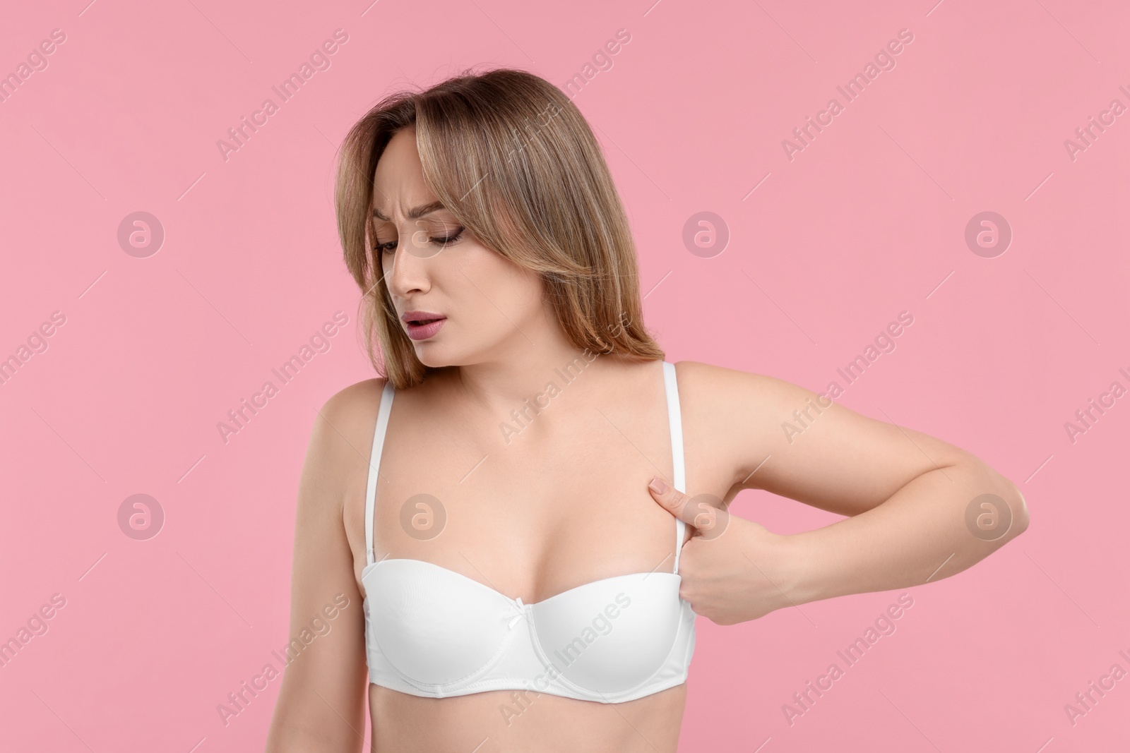 Photo of Mammology. Young woman doing breast self-examination on pink background