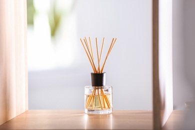 Photo of Aromatic reed air freshener on table against blurred background