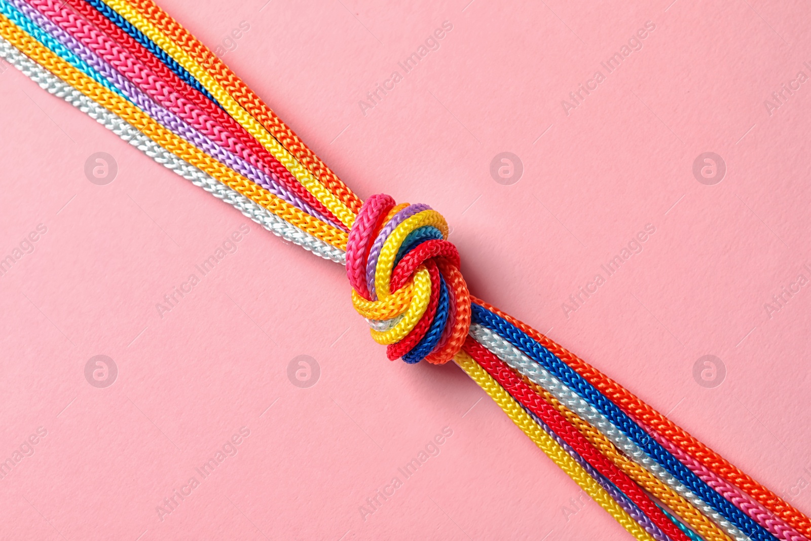 Photo of Different ropes tied together with knot on color background. Unity concept