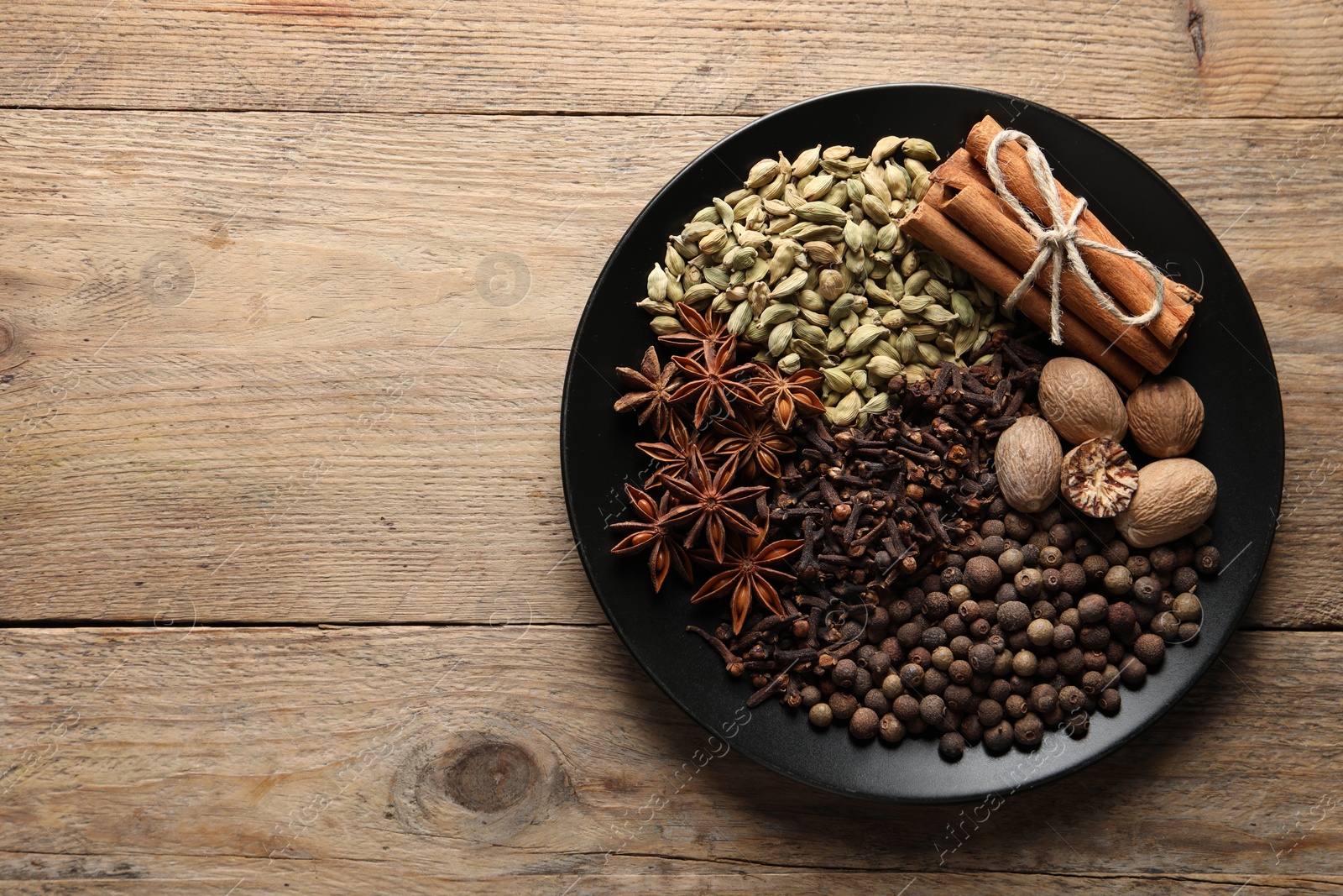 Photo of Different spices and nuts on wooden table, top view. Space for text