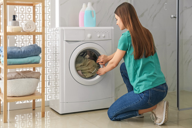 Woman near washing machine in bathroom. Laundry day