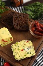 Photo of Tasty butter with green onion, chili peppers, rye bread and dill on table