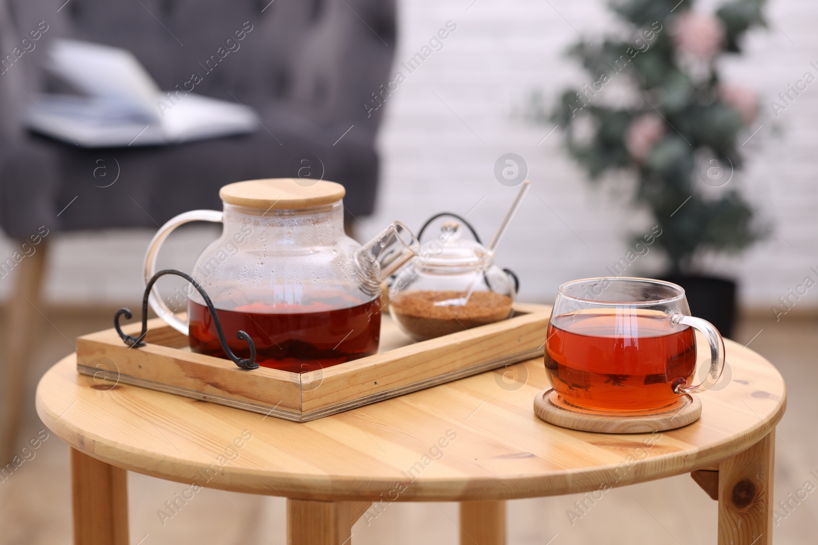 Photo of Teapot, cup of aromatic tea and brown sugar on wooden table indoors