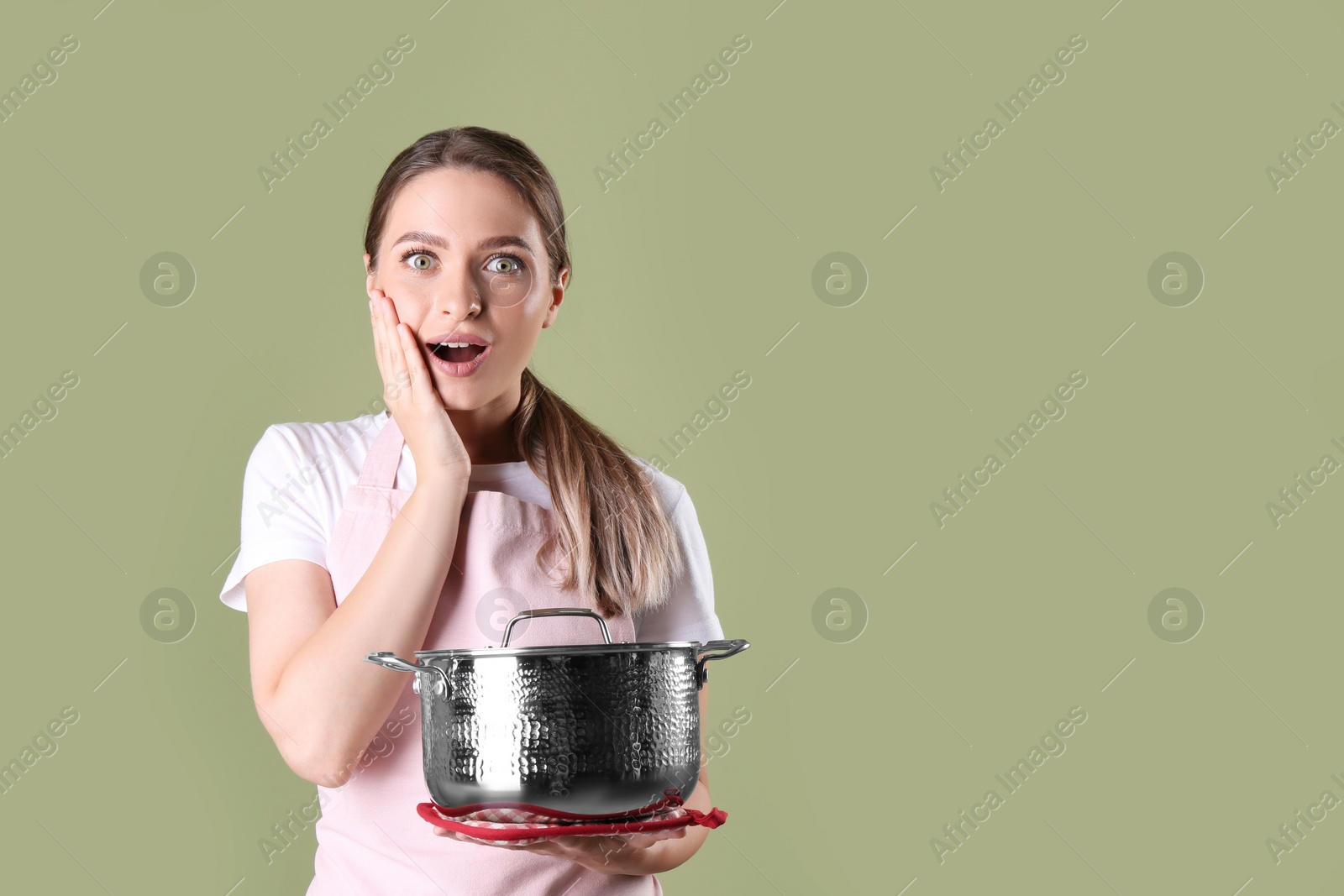 Photo of Surprised woman with pot on olive background, space for text