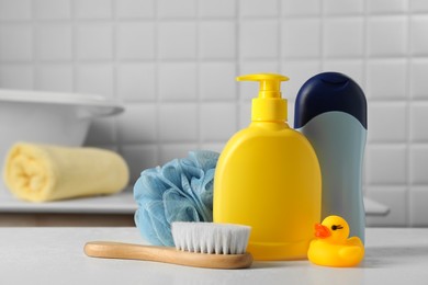 Photo of Baby cosmetic products, bath duck, brush and cotton swabs on white table