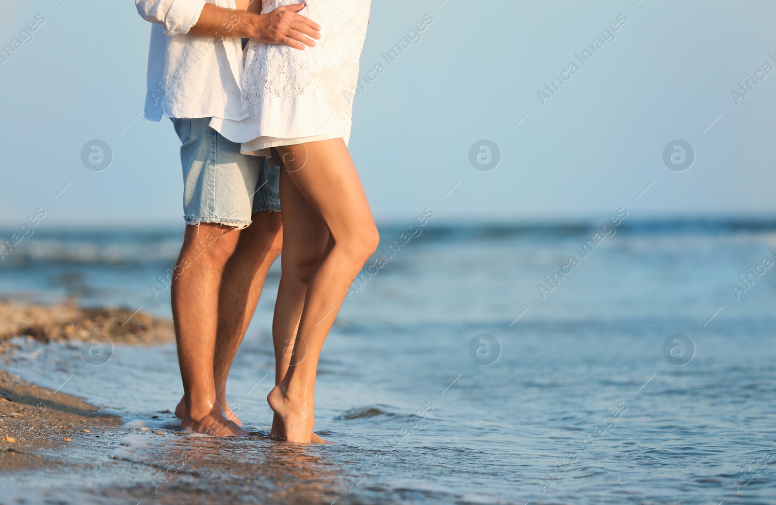 Photo of Young couple spending time together on beach, focus on legs