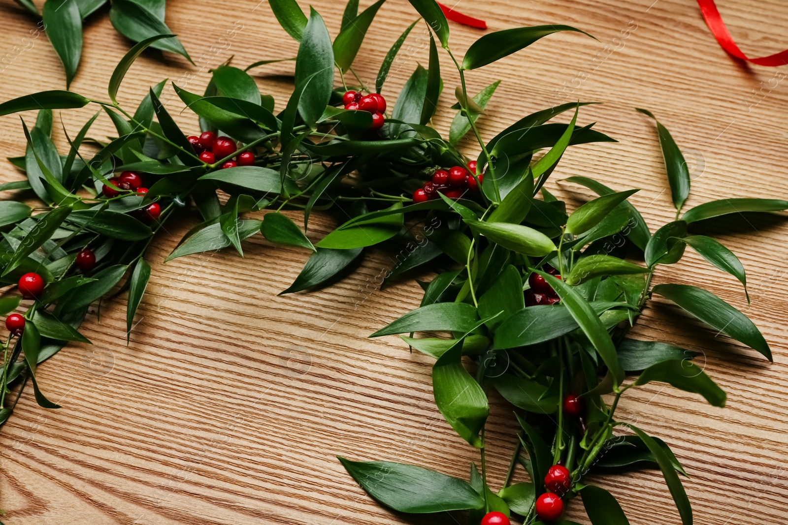 Photo of Beautiful mistletoe wreath on wooden table, closeup. Traditional Christmas decor