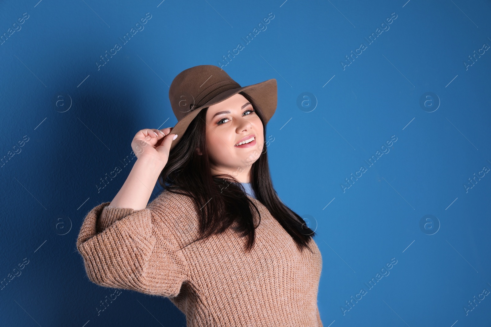 Photo of Beautiful overweight woman posing on blue background. Plus size model