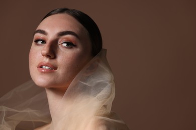 Fashionable portrait of beautiful woman with fake freckles on brown background. Space for text