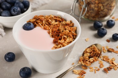 Delicious yogurt with granola and blueberries served on grey marble table, closeup
