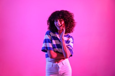 Photo of Beautiful young woman posing on color background in neon lights