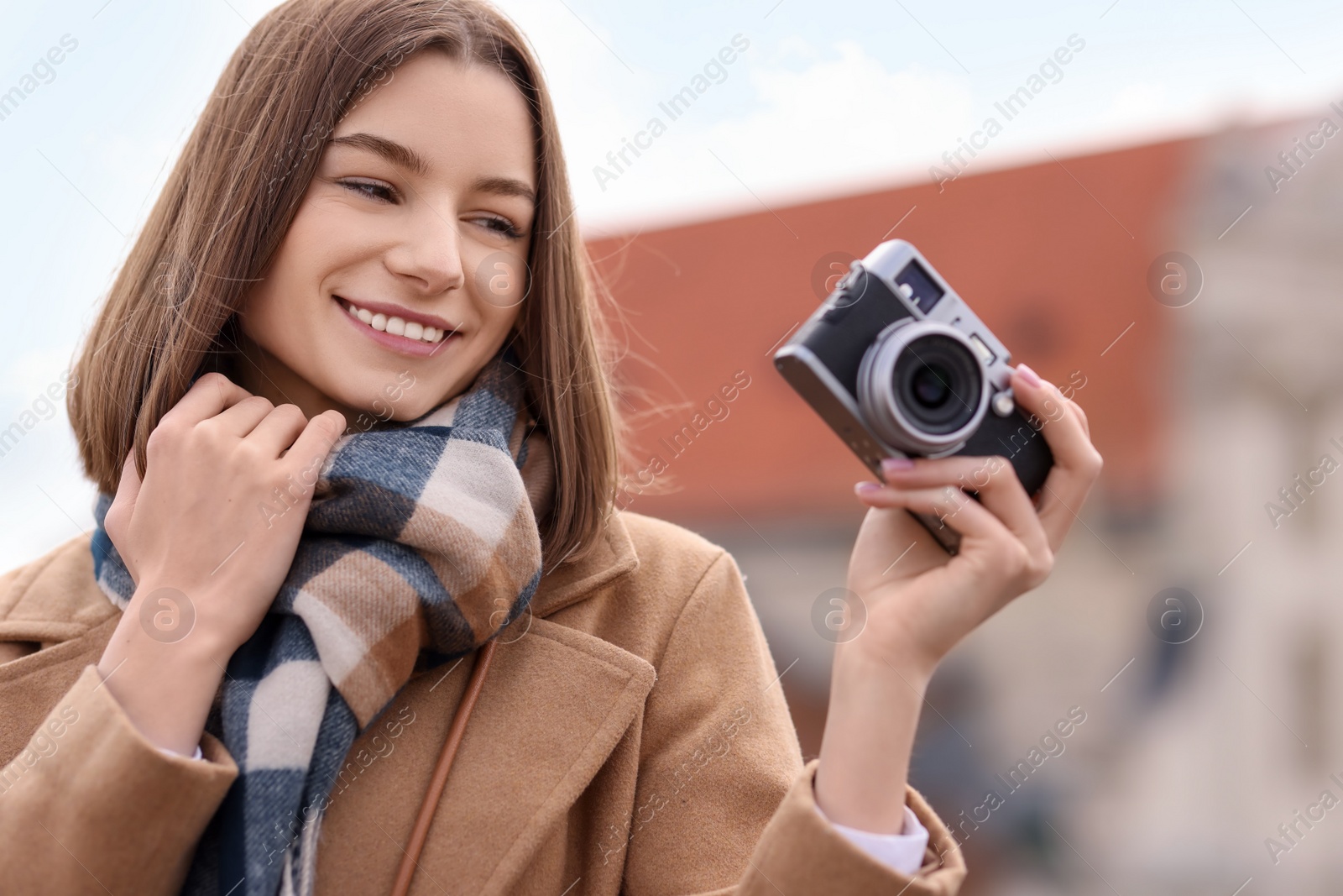 Photo of Beautiful woman in warm scarf with vintage camera outdoors