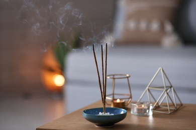 Photo of Incense sticks smoldering on table indoors, space for text