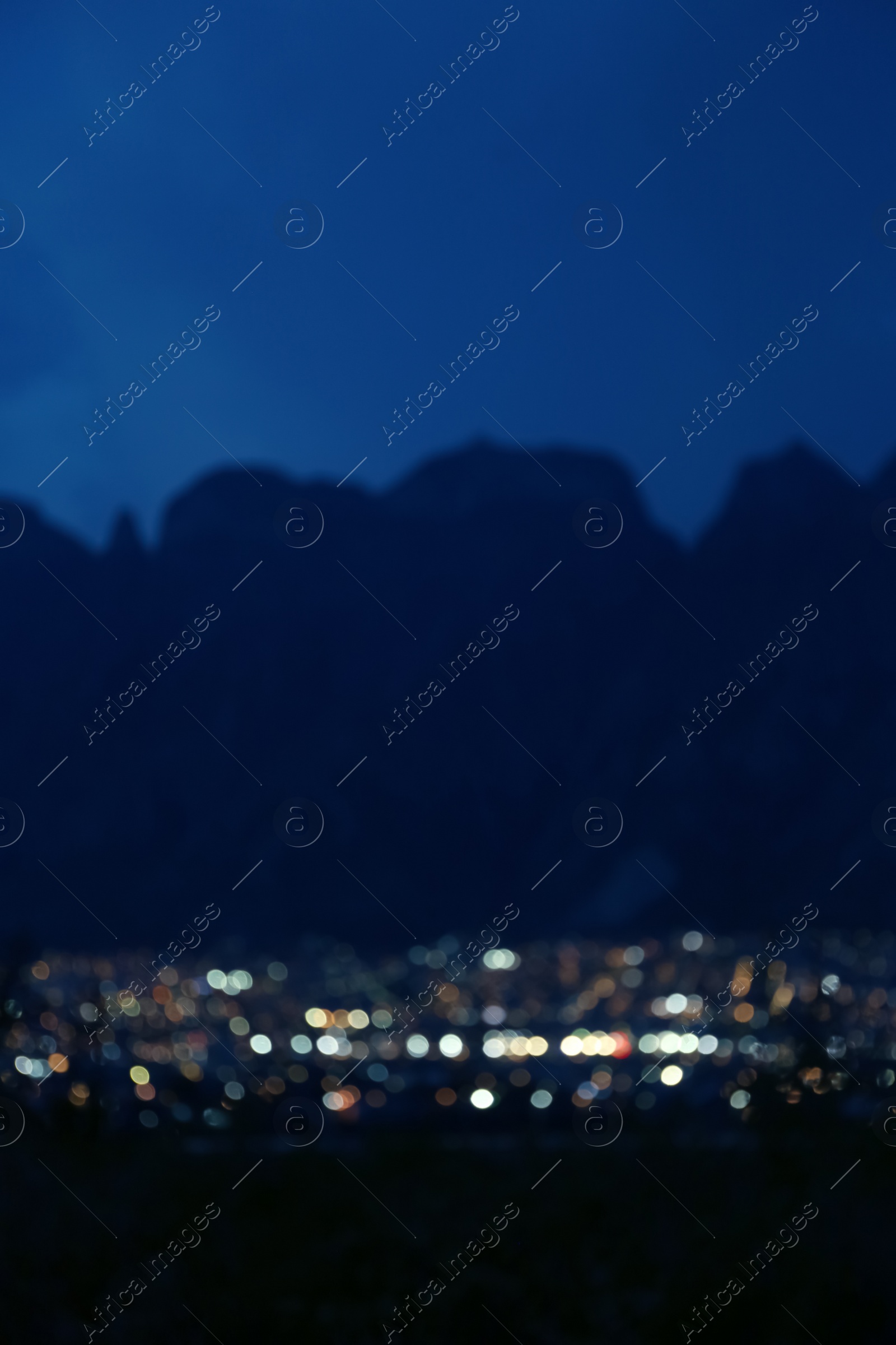 Photo of Blurred view of beautiful city near mountains at night. Bokeh effect