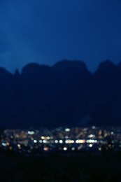 Photo of Blurred view of beautiful city near mountains at night. Bokeh effect