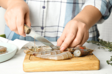 Photo of Woman cutting fresh shrimp at table, closeup