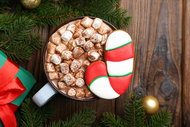 Photo of Tasty Christmas cookie in shape of candy cane, decor and cocoa with marshmallows on wooden table, flat lay. Space for text