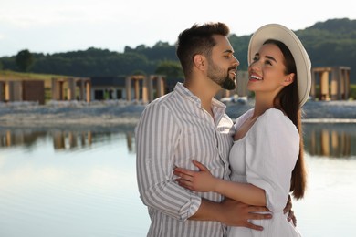 Photo of Romantic date. Beautiful couple spending time together near lake, space for text