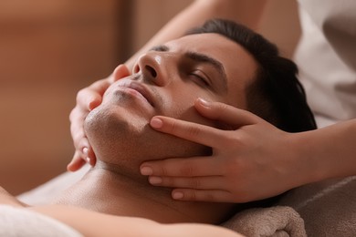 Photo of Man receiving facial massage in beauty salon, closeup