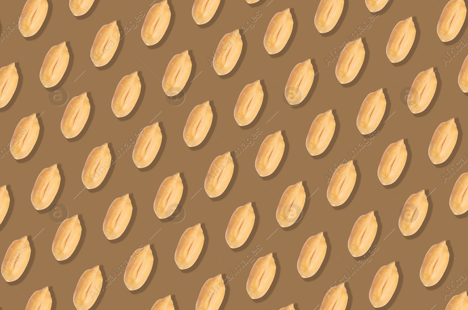 Image of Pattern of peeled peanuts on brown background