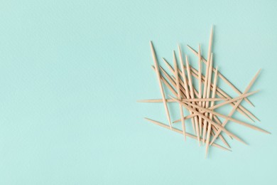 Photo of Wooden toothpicks on light blue background, flat lay. Space for text