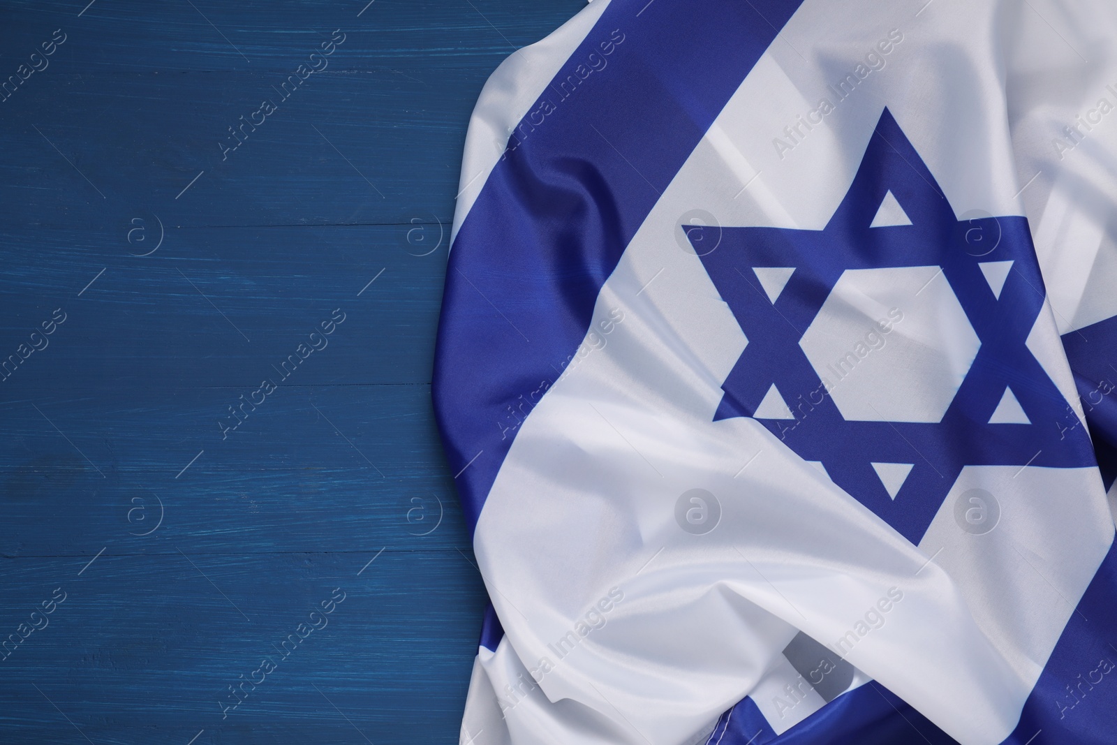 Photo of Flag of Israel on blue wooden background, top view and space for text. National symbol