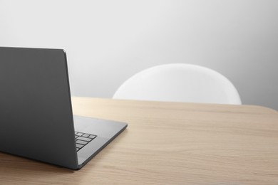 Photo of Stylish modern laptop on wooden table indoors. Space for text