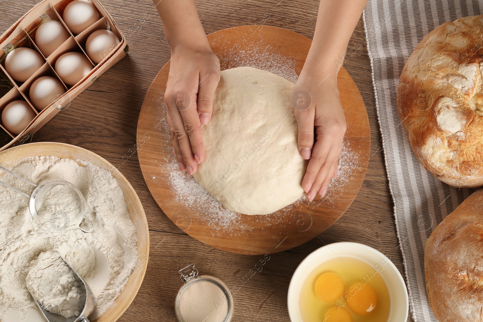 Photo of Female baker preparing bread dough at kitchen table, top view