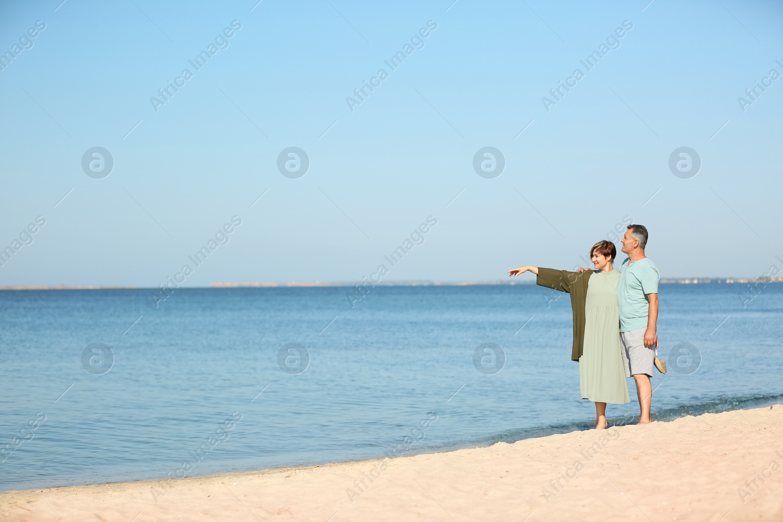 Photo of Happy mature couple walking at beach on sunny day