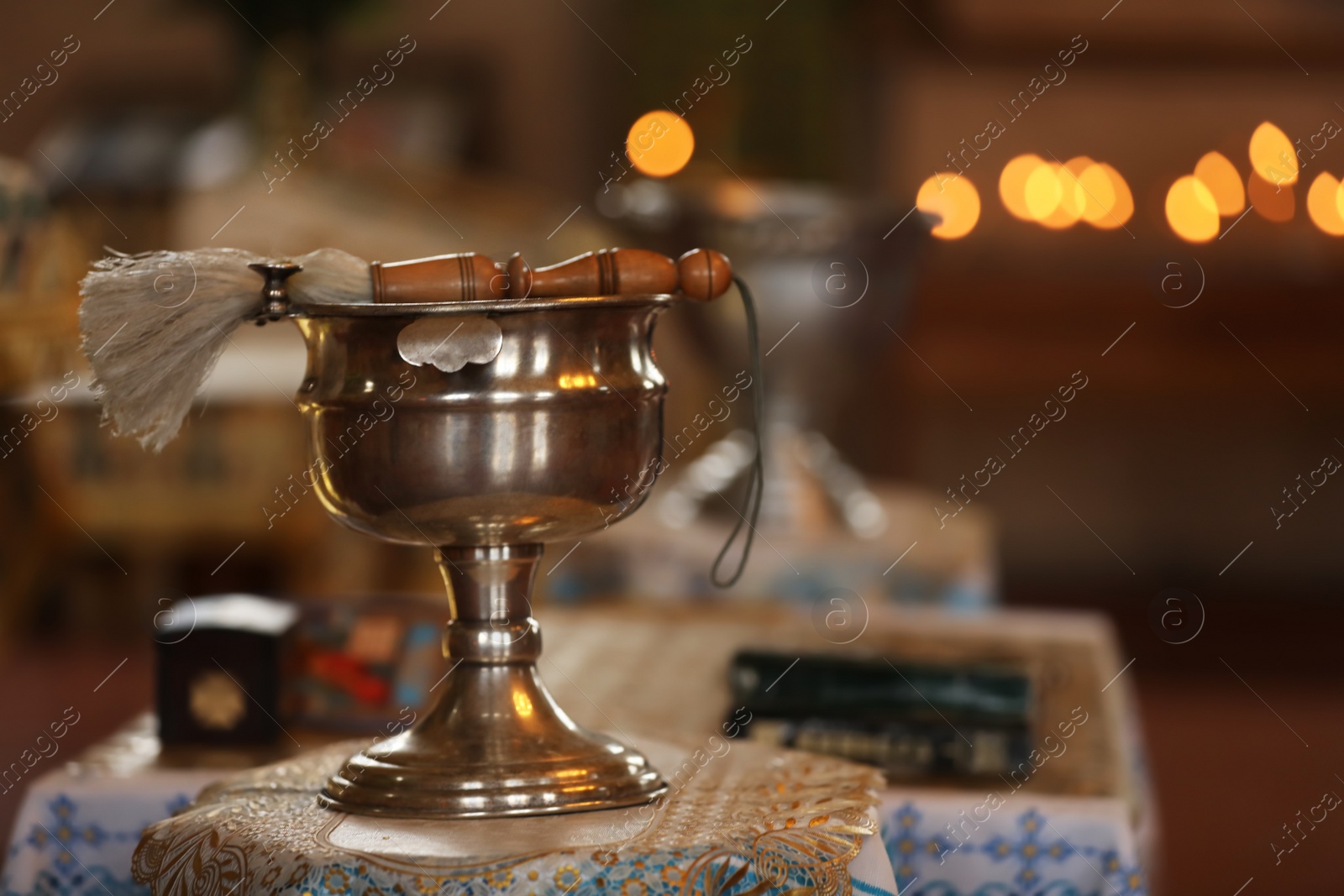 Photo of Silver vessel with holy water and brush on stand in church, space for text. Baptism ceremony