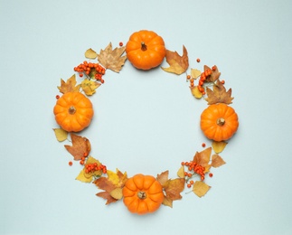 Frame made of ripe pumpkins, autumn leaves and berries on light blue background, flat lay. Space for text