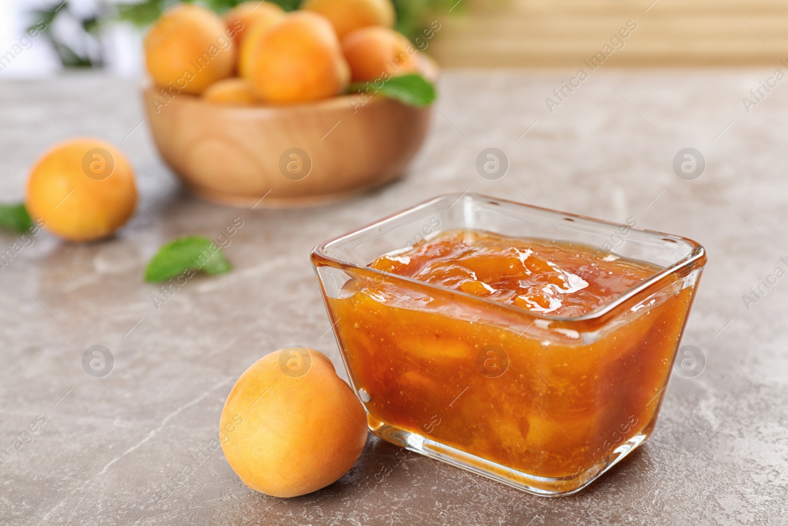 Photo of Bowl with tasty apricot jam on table