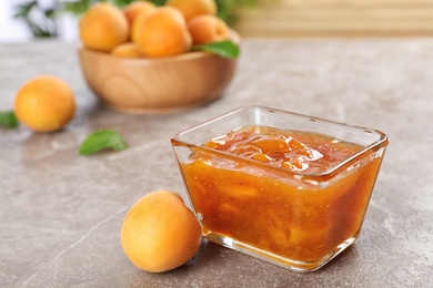 Photo of Bowl with tasty apricot jam on table