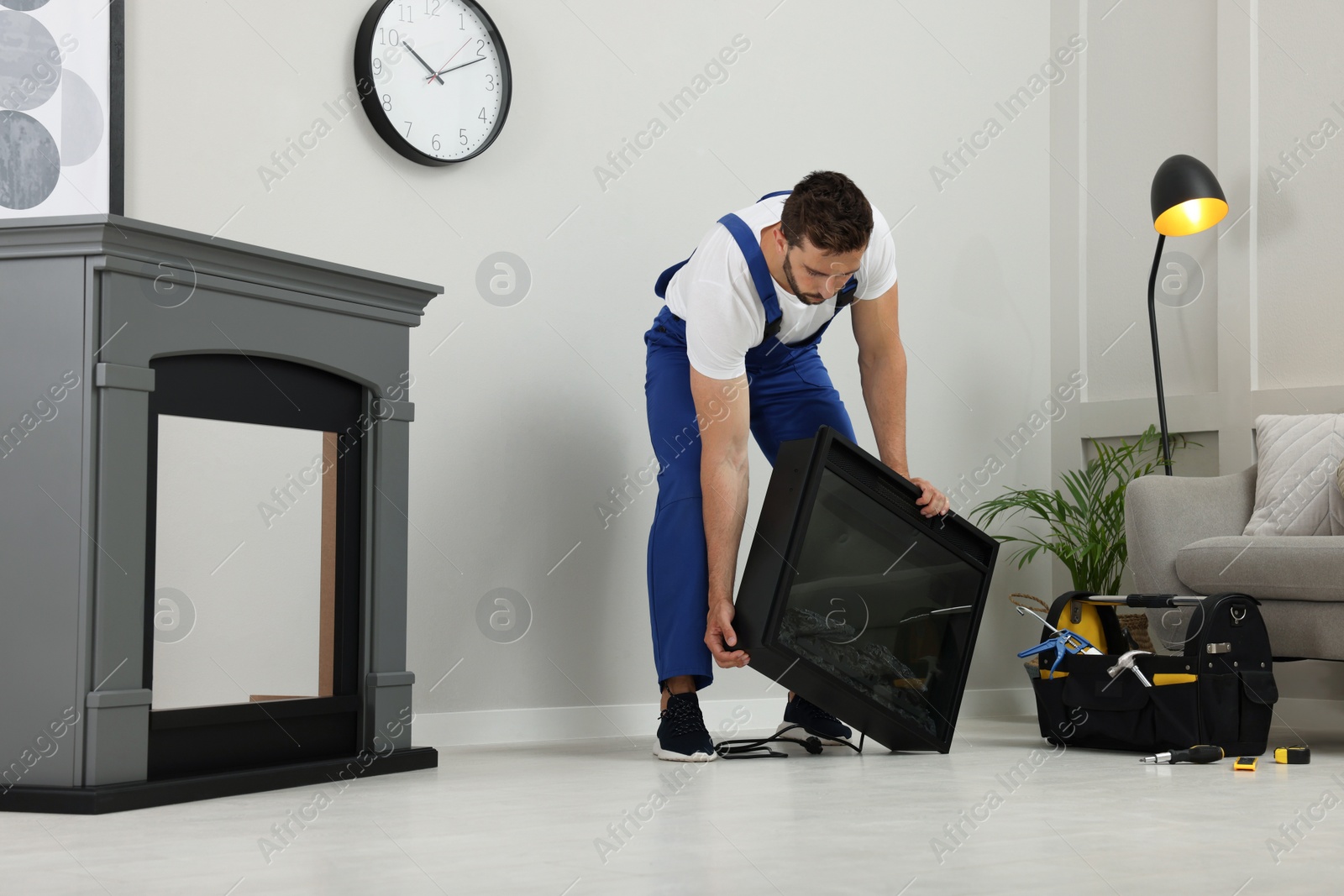 Photo of Professional technician installing electric fireplace in room