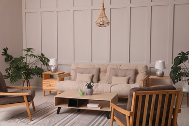 Stylish living room interior with comfortable sofa, armchairs and beautiful plants