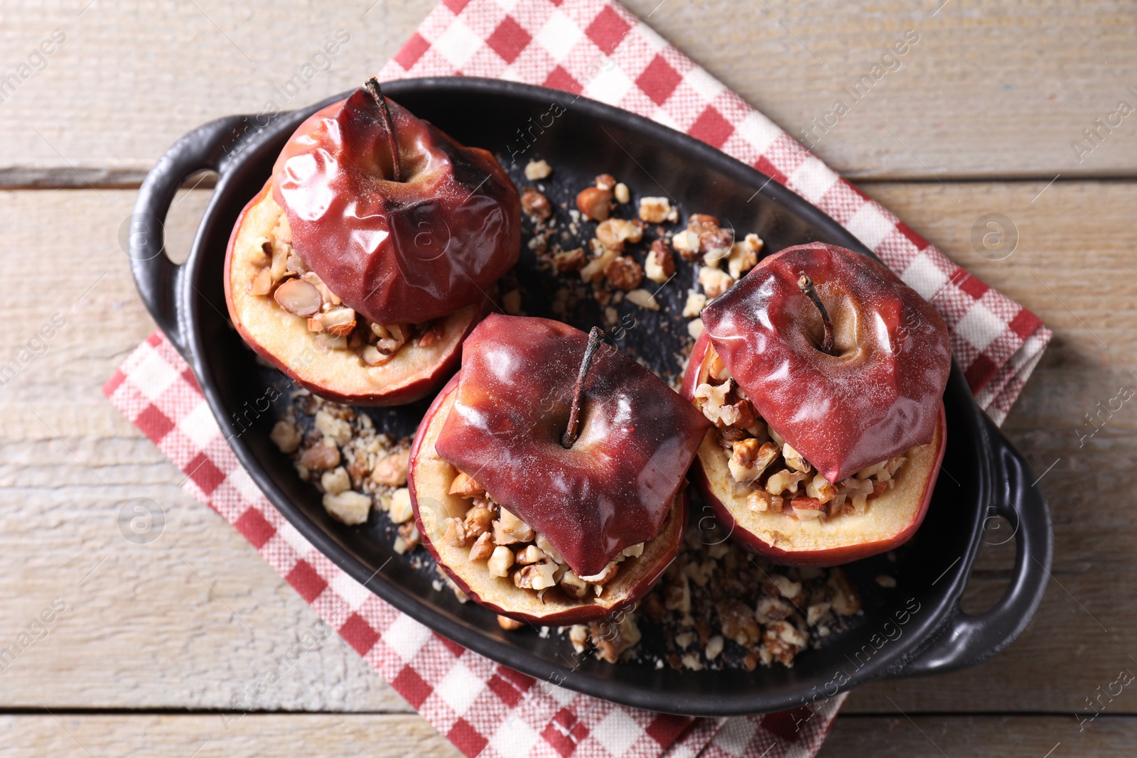 Photo of Tasty baked apples with nuts in baking dish on wooden table, top view