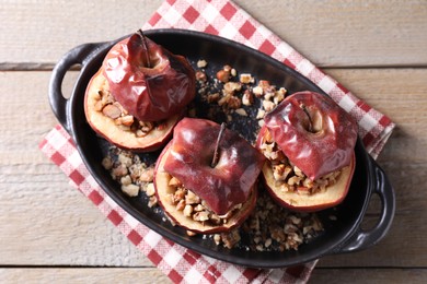 Photo of Tasty baked apples with nuts in baking dish on wooden table, top view