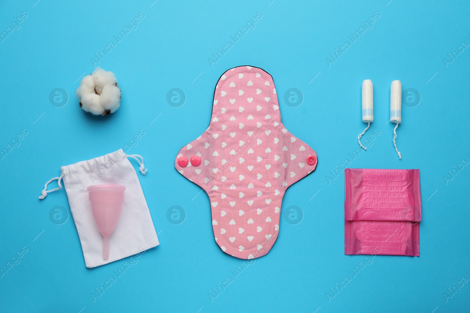 Photo of Cloth menstrual pad near other reusable and disposable female hygiene products on light blue background, flat lay