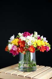 Photo of Bouquet of spring freesia flowers in vase on dark background. Space for text