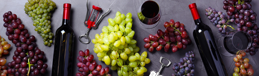 Flat lay composition with fresh ripe juicy grapes and wine on grey table. Banner design